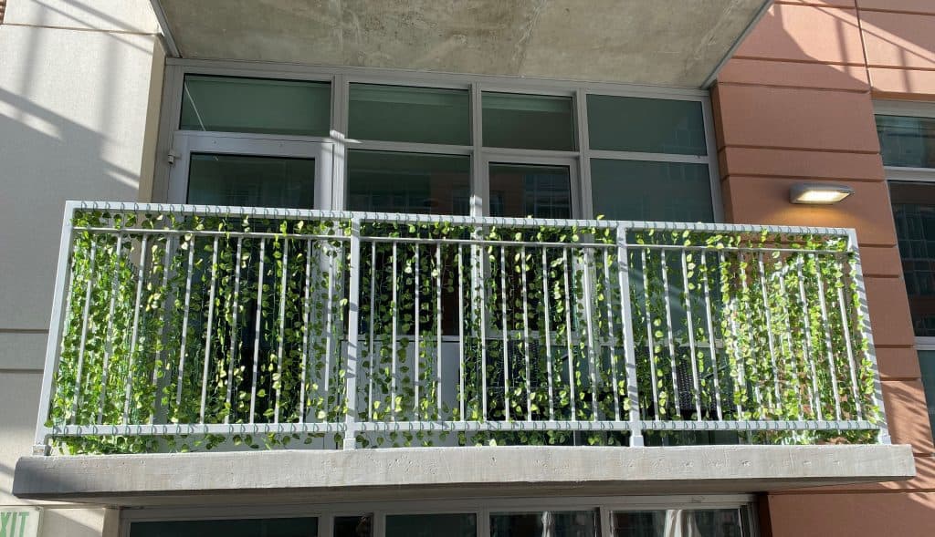 a balcony with hanging strands of fake greenery for privacy