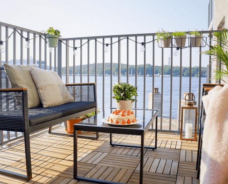 a high rise balcony with outdoor furniture, string lights and decking tiles